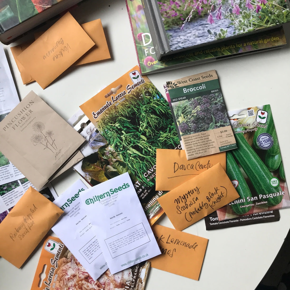 A smattering of seed packets from Chilterns, saved seeds in Kraft paper envelopes and West Coast Seeds