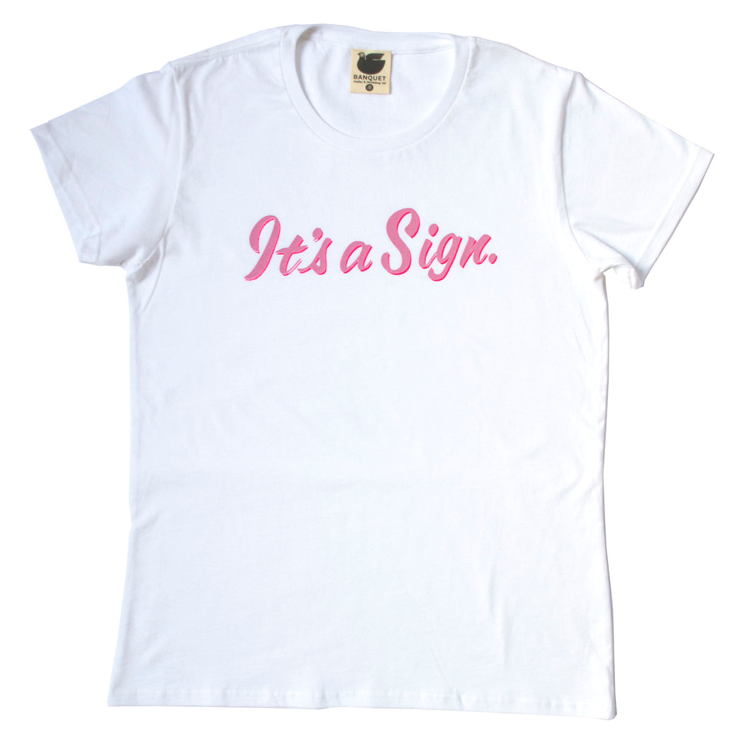white t-shirt screen printed with "It's a Sign" in pink on pink cursive